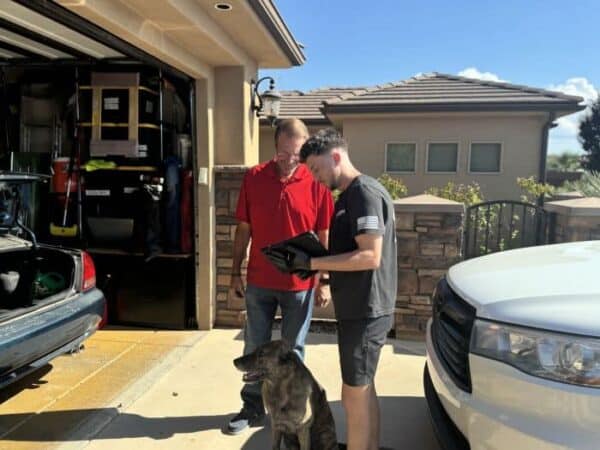 Garage door service technician discussing details with a homeowner in front of a loaded garage.